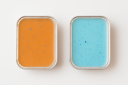 Two wax melts, one orange and one blue, with speckled patterns on a white background.