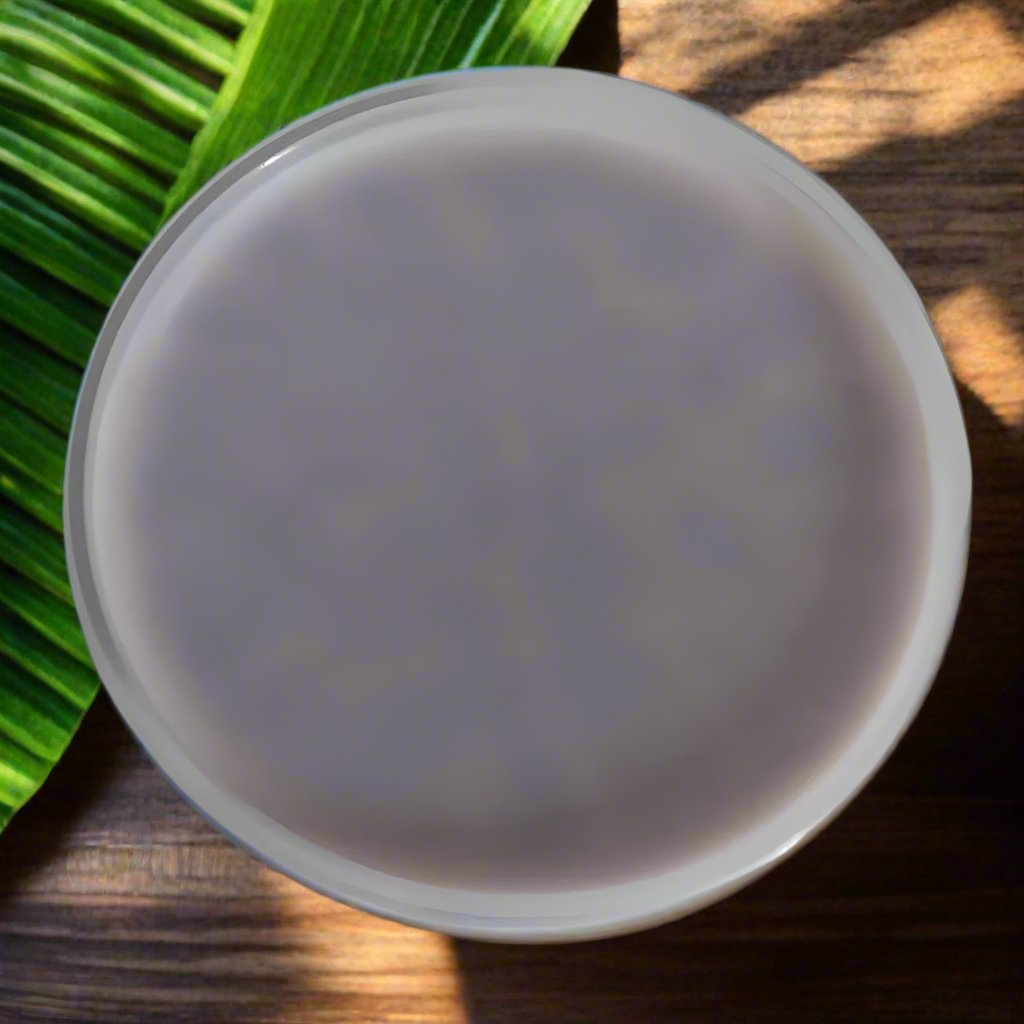 All-natural scoopable wax melts in a white bowl resting on a wooden surface and green leaf.