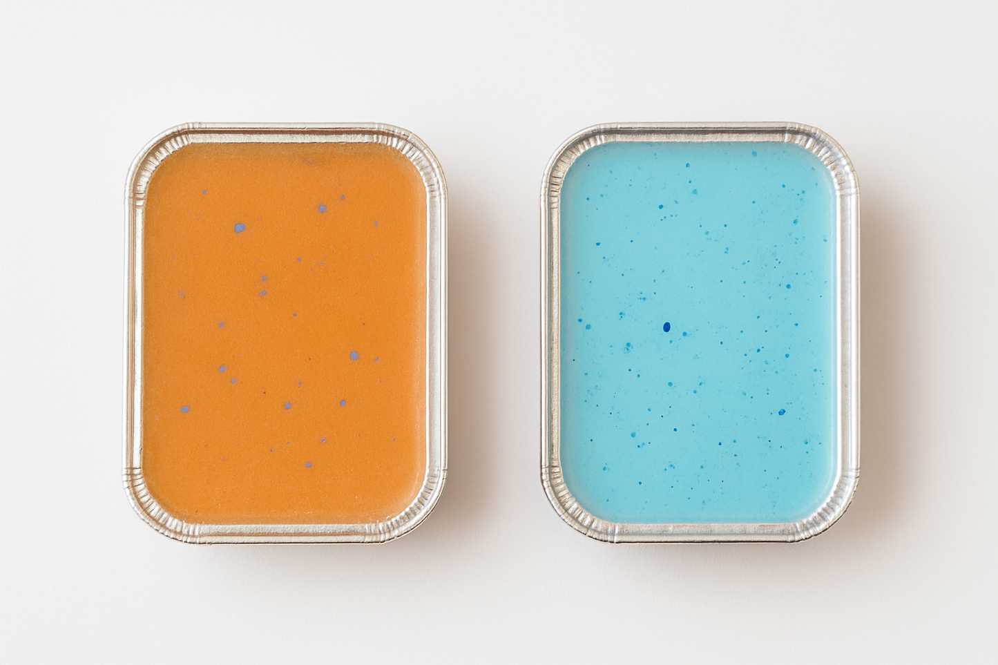 Two wax melts, one orange and one blue, with speckled patterns on a white background.